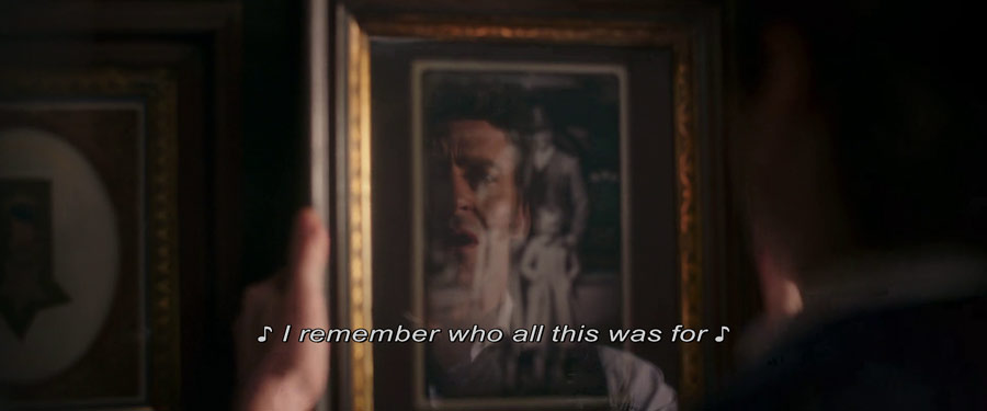 Barnum looking at a photo of his family while singing that he remembers who all this was for